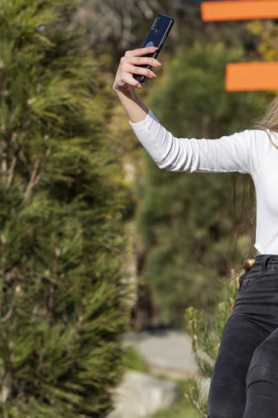 Mulher fazendo uma selfie segurando um copo de café, exemplo de registro estratégico para fazer marketing para cafeteria