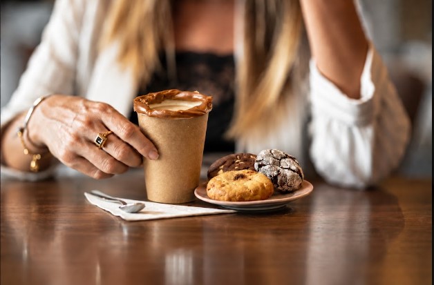 Foto com foco na experiência do cliente durante o consumo de café e cookies para a estratégia de marketing para cafeteria