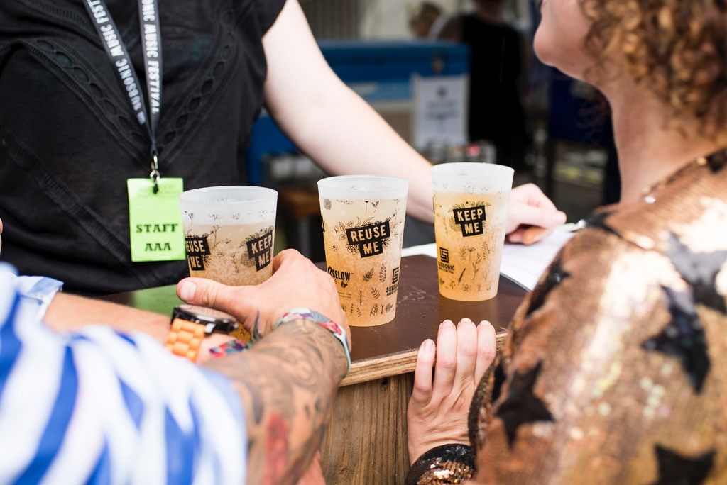 Clientes pegam copos ecológicos de cerveja sobre um balcão