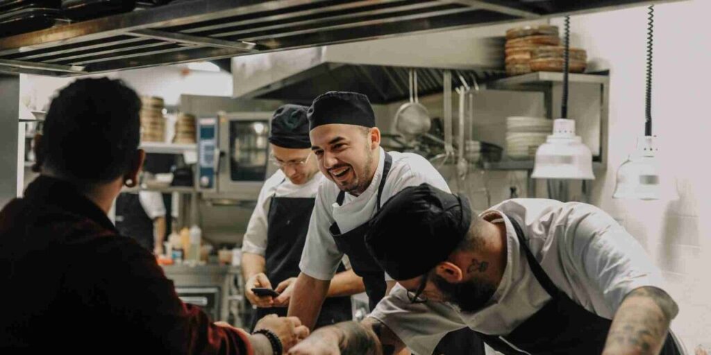 4 pessoas conversando e sorrindo em uma cozinha de restaurante