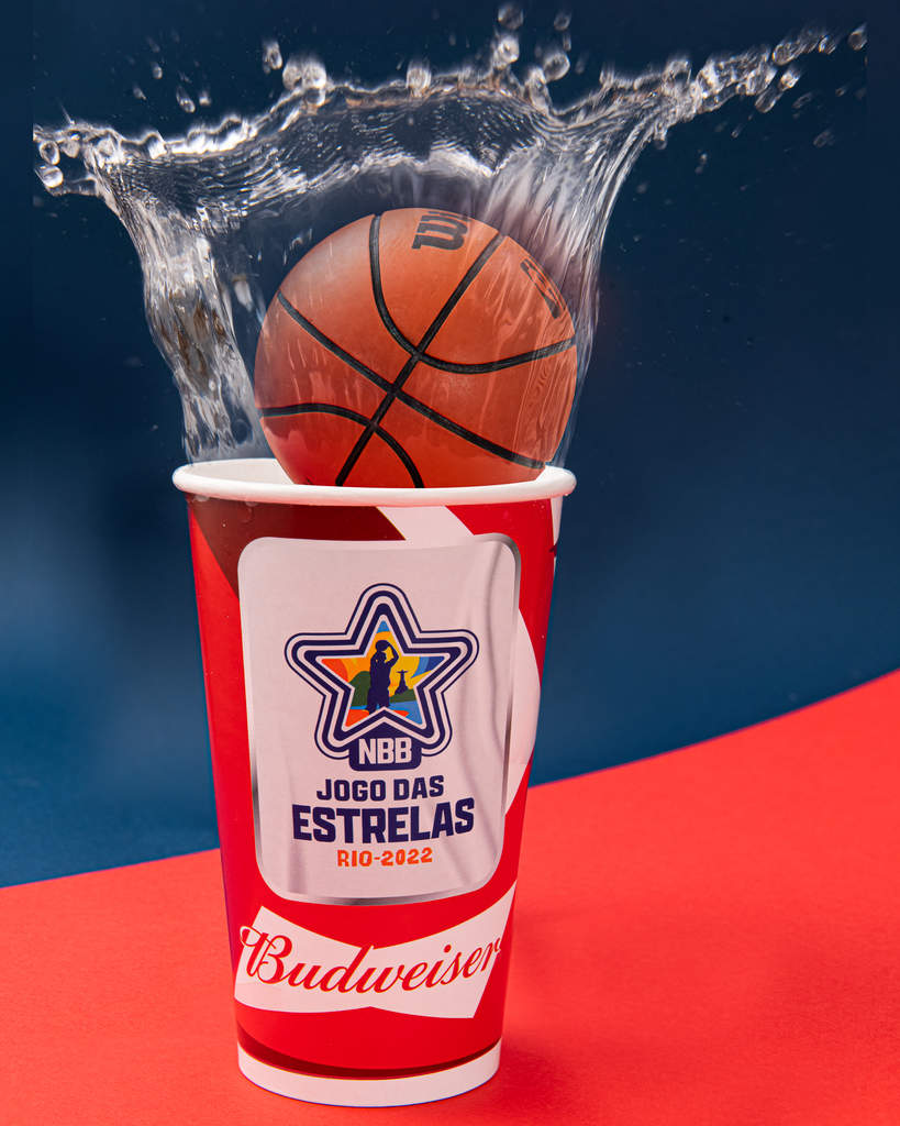 Copo para evento caindo uma mini bola de basquete nele e espirrando água para foto. No copo há um logotipo com os dizeres NBB Jogo das Estrelas, Rio 2022 e "Budweiser" embaixo