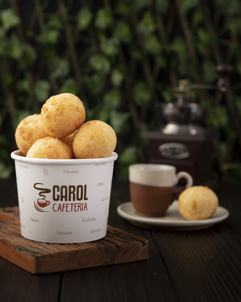 Pote com pães de queijo personalizado com o logotipo "Carol Cafeteria" e palavras como: Fé, Gratidão, Felicidade, Amor etc. Representando embalagens personalizadas, que são uma ótima estratégia de marketing para delivery 