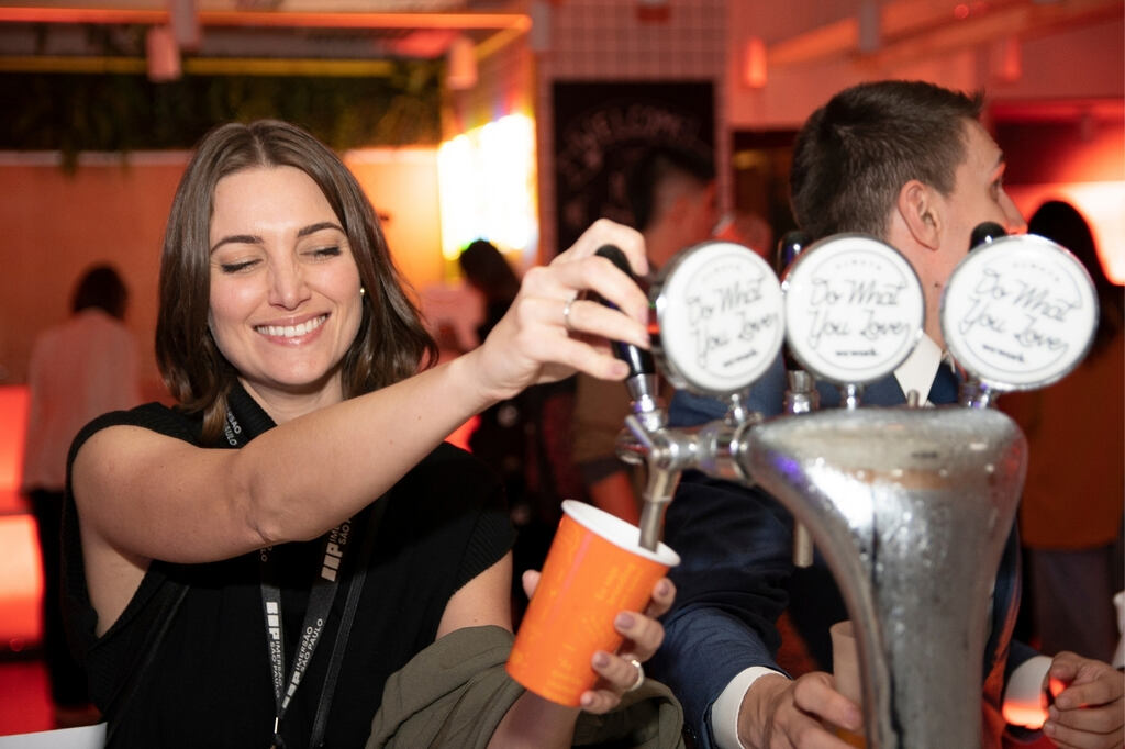 Mulher servindo bebida em copo de papel personalizado no bar de festival