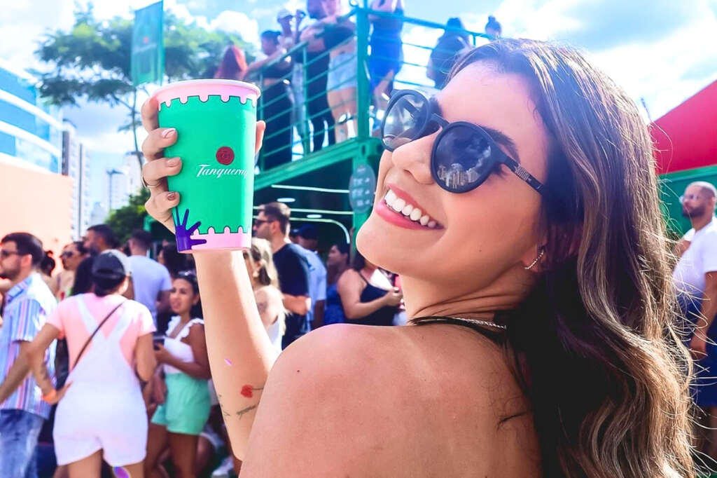 Mulher com copo de papel personalizado da Tanqueray na mão em grande evento