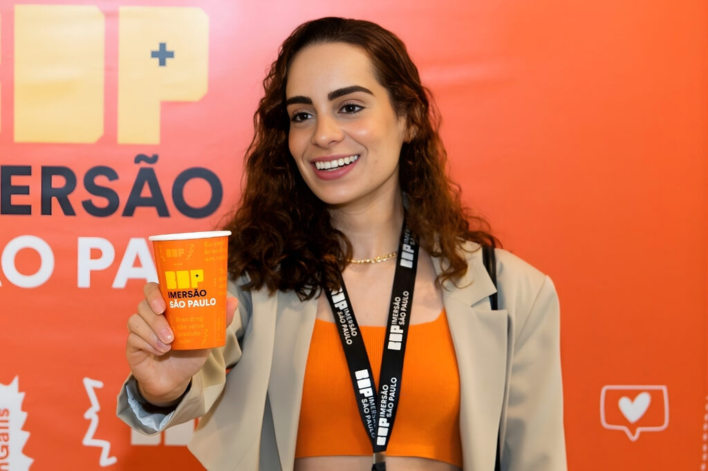 Mulher segurando copo de papel em evento, mostrando a personalização de copos para fortalecimento da marca