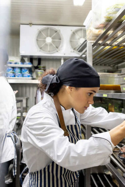 Mulher mexendo em embalagens em cozinha de restaurante