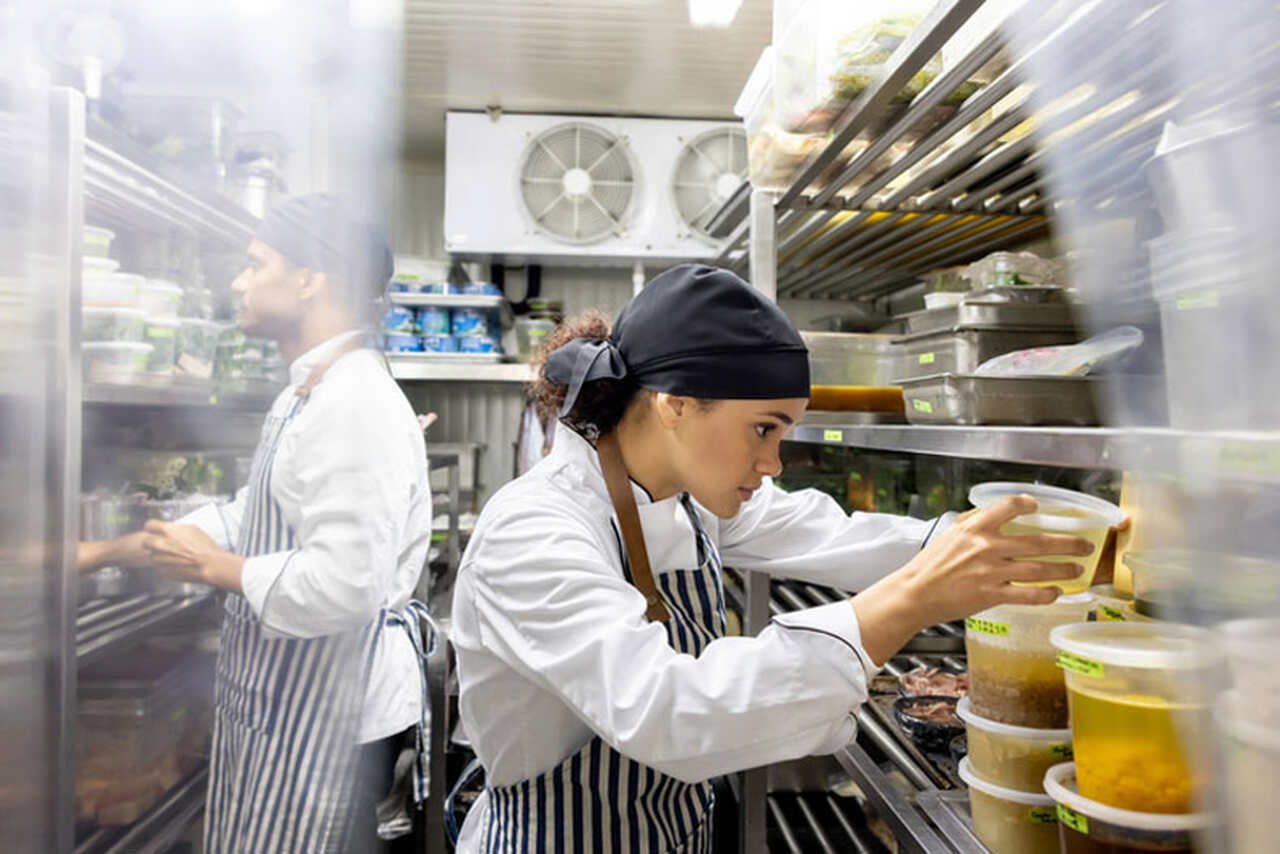 Mulher mexendo em embalagens em cozinha de restaurante