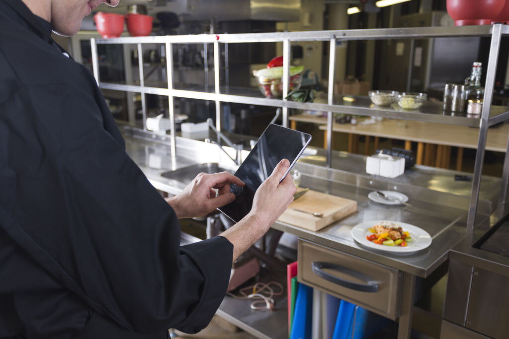 Homem calculando em tablet quanto custa para abrir um restaurante