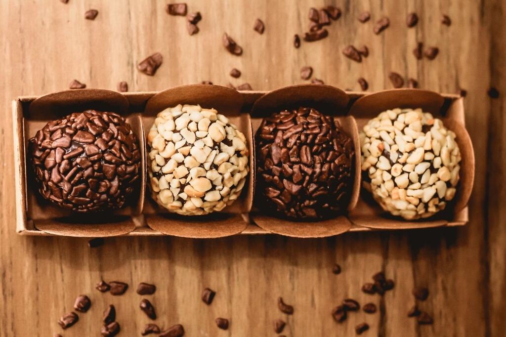 Caixa de papel com brigadeiros tradicionais e de amendoim, um exemplo de embalagem para doces finos que para ser usadas em encomendas